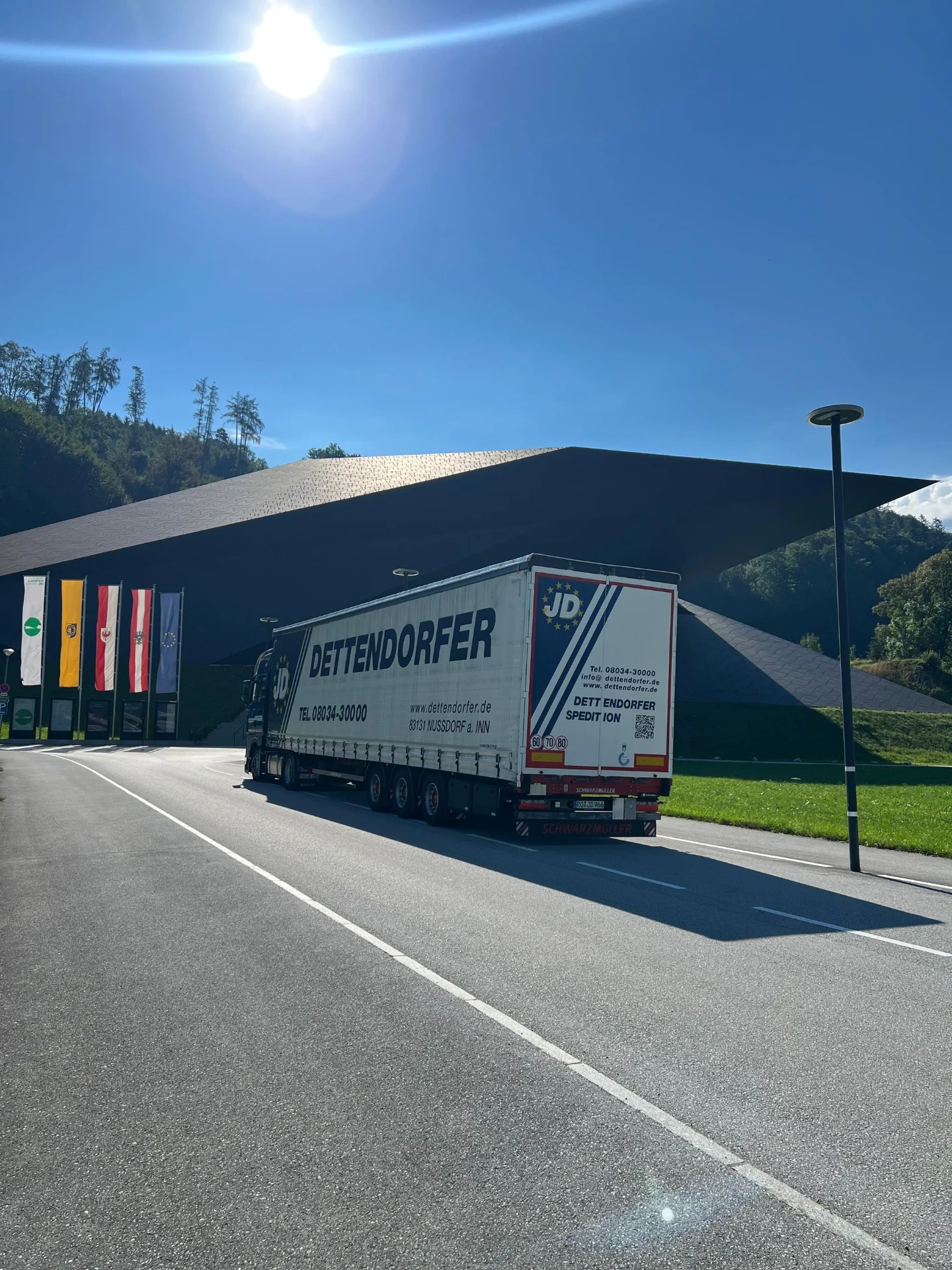 Dettendorfer LKW im regionalen Einsatz vor modernem Gebäude